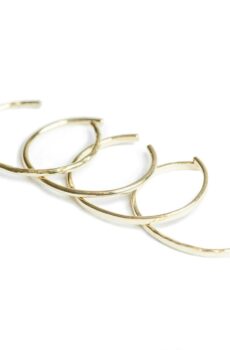 Four thin gold bangles set out on a white background.