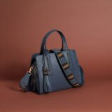A navy blue bag with a beaded strap and tassel.
