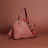 A dark red leather handbag with a zippered top, handles and a beaded brown, black, and red shoulder strap.