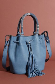 A blue bag with handles, a strap, and a drawstring decorated with tassels