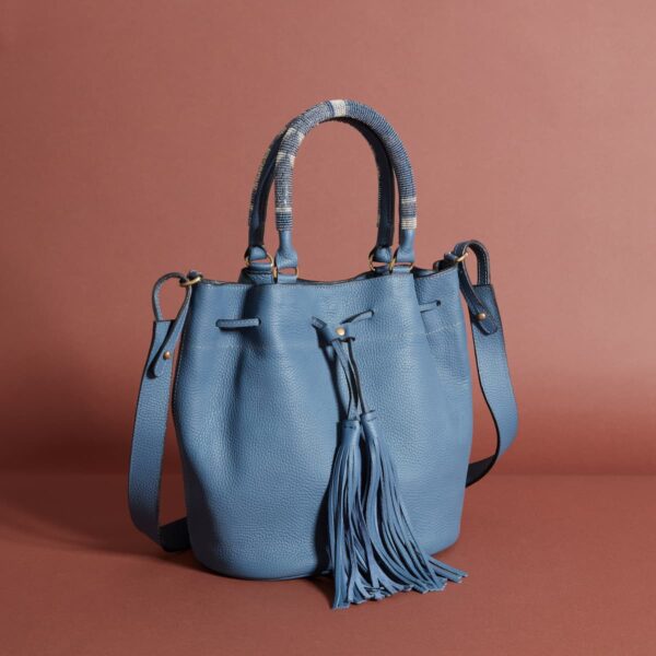 A blue bag with handles, a strap, and a drawstring decorated with tassels