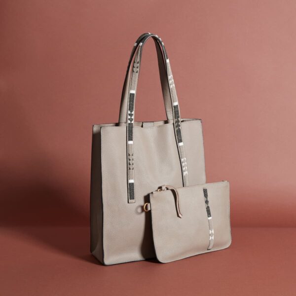 A muted beige toat back with a long strap and a smaller clutch-style back of the same color in front of it