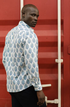 A man wearing a blue patterned button up shirt on a white background