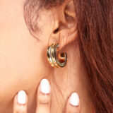 person wearing 24K gold-plated recycled brass earrings with recycled horn/bone inlay