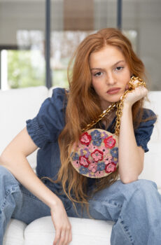 person holding round floral raffia bag